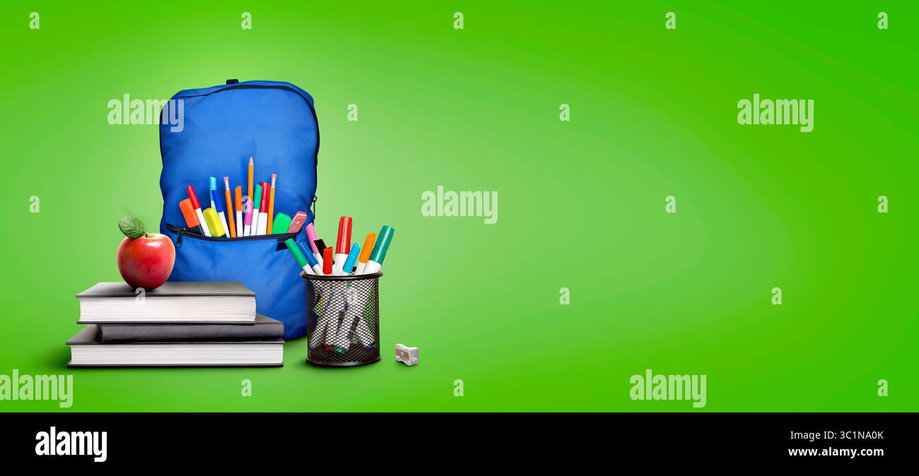 A back to school scene of a pile of three study books to learn from, yellow school bag and pens and pencils against a green background with copy space Stock Photo