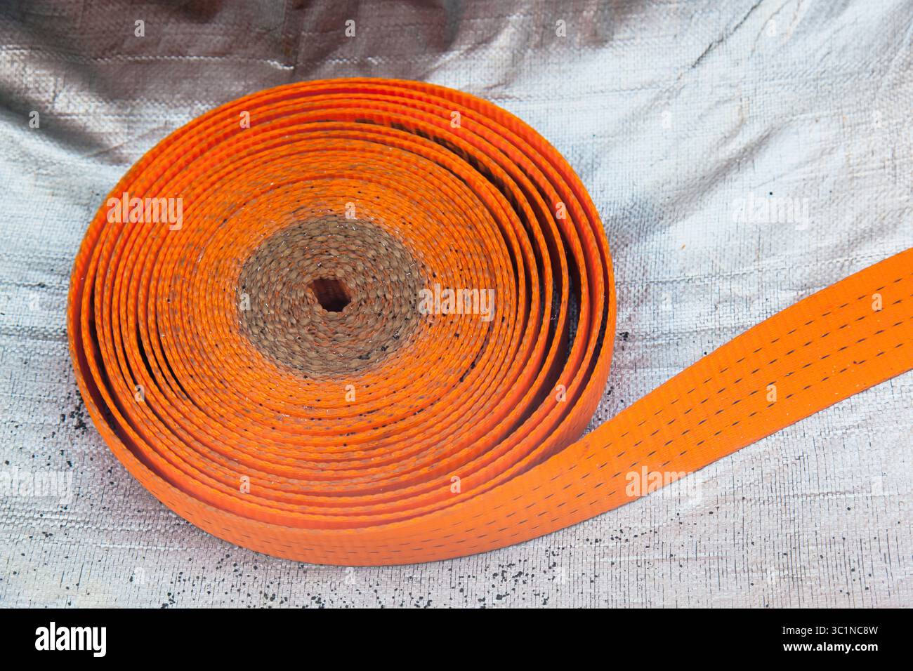 Strap for securing cargo lies on a blue - gray plastic bag in close-up. Stock Photo