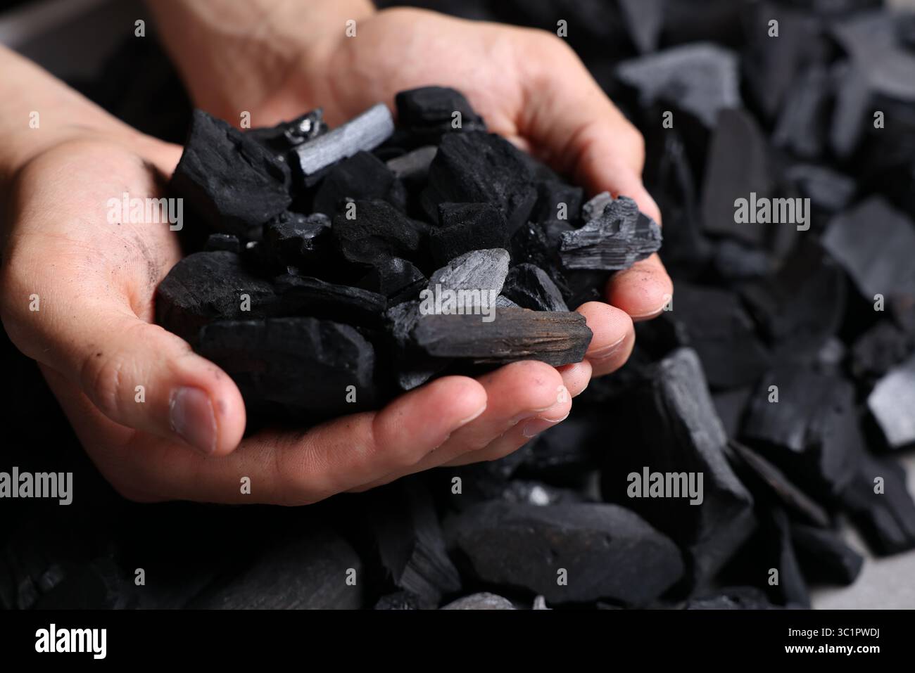 Man with black coals over pile, closeup Stock Photo