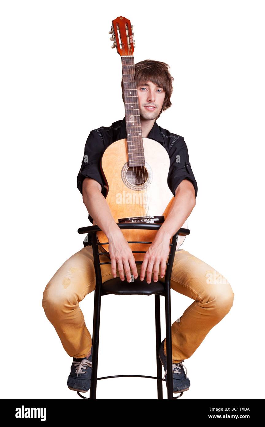 A talented musician sits on a stool with a guitar, showcasing his passion for music. Stock Photo