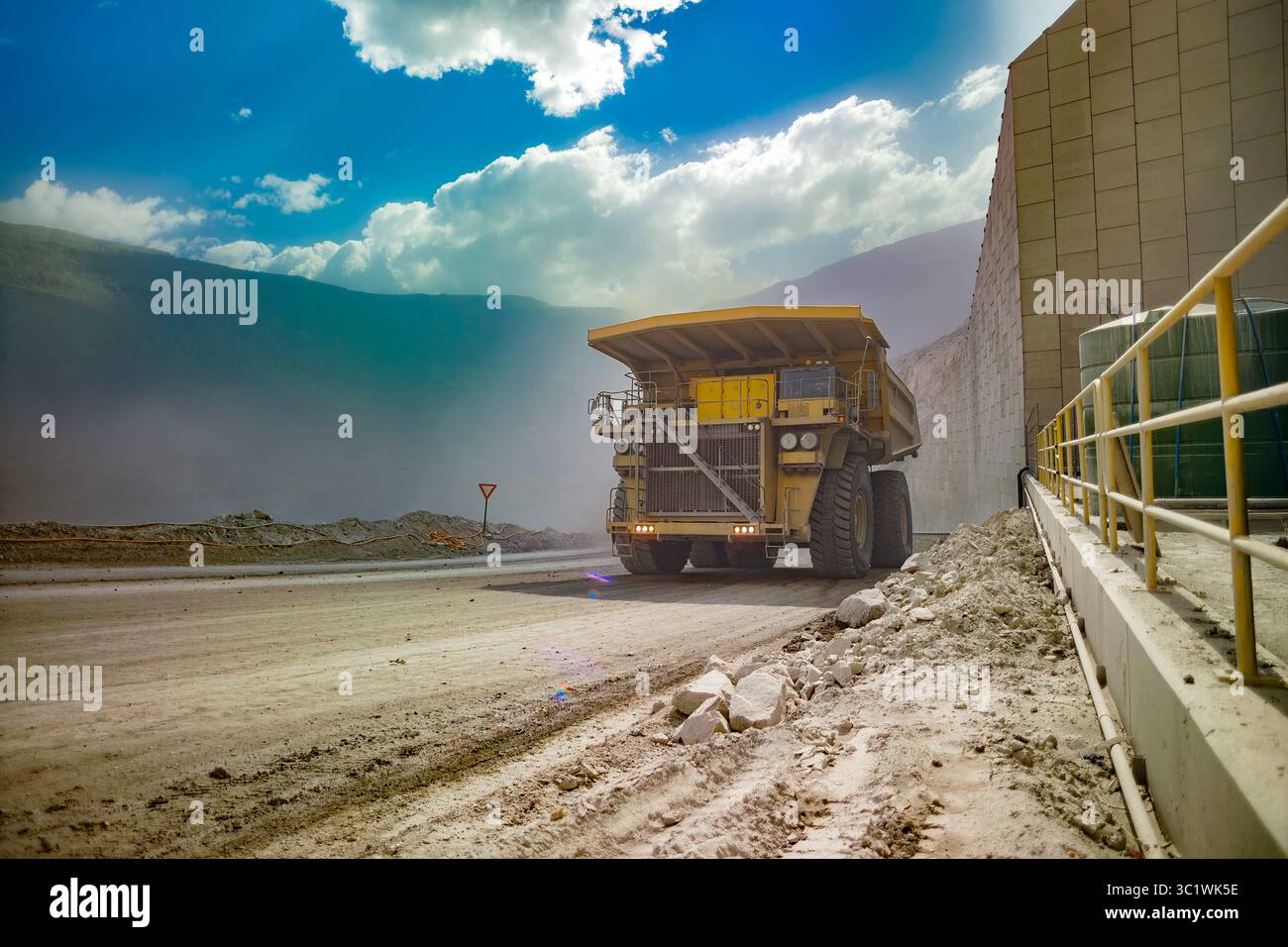 The sheer scale of a Chilean open-pit copper mine, featuring a huge haul truck under a dramatic sky. Stock Photo