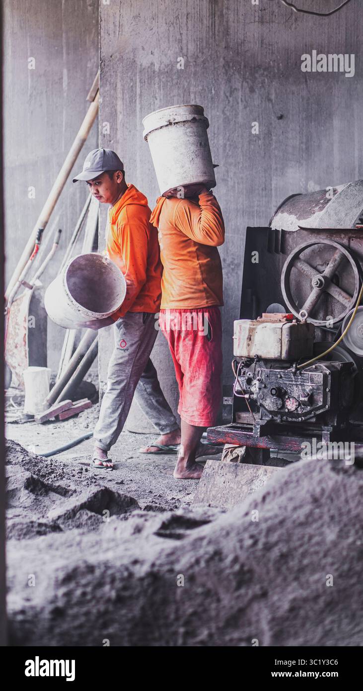 Construction workers collaborate in mixing cement, showcasing solid teamwork and efficiency in real on-site building operations. Stock Photo