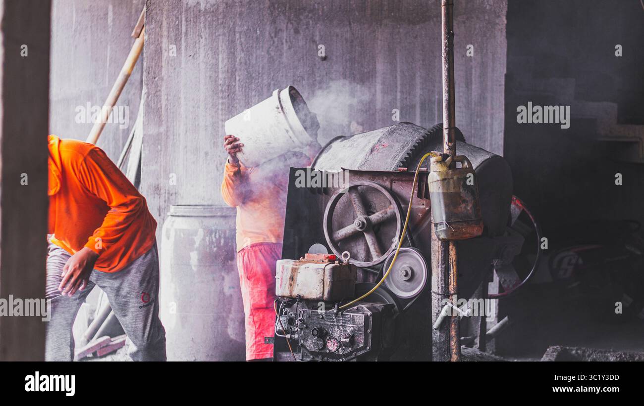 Construction workers collaborate in mixing cement, showcasing solid teamwork and efficiency in real on-site building operations. Stock Photo