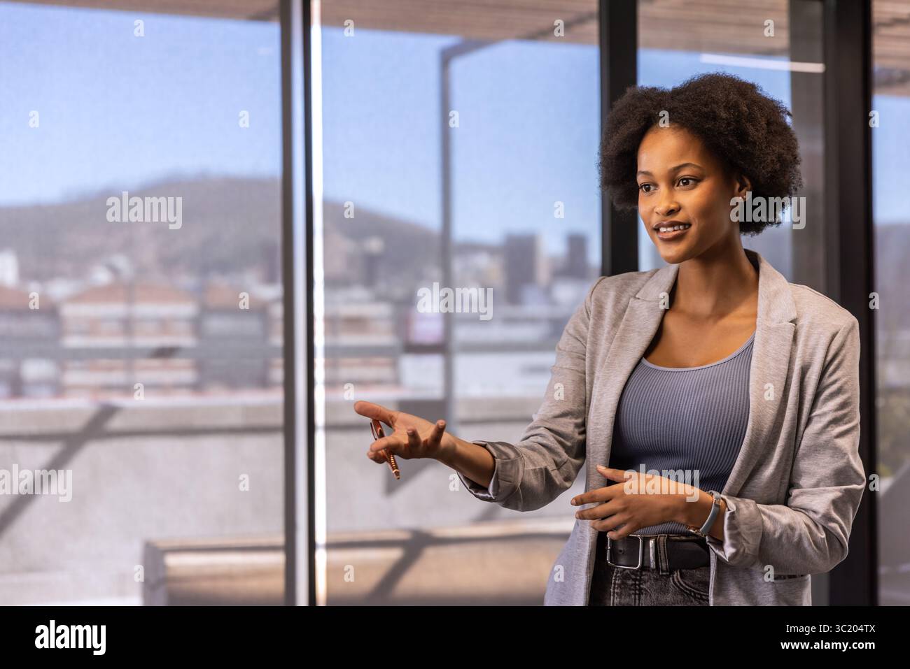 African American businesswoman in business attire presenting at glass panels in office, copy space Stock Photo