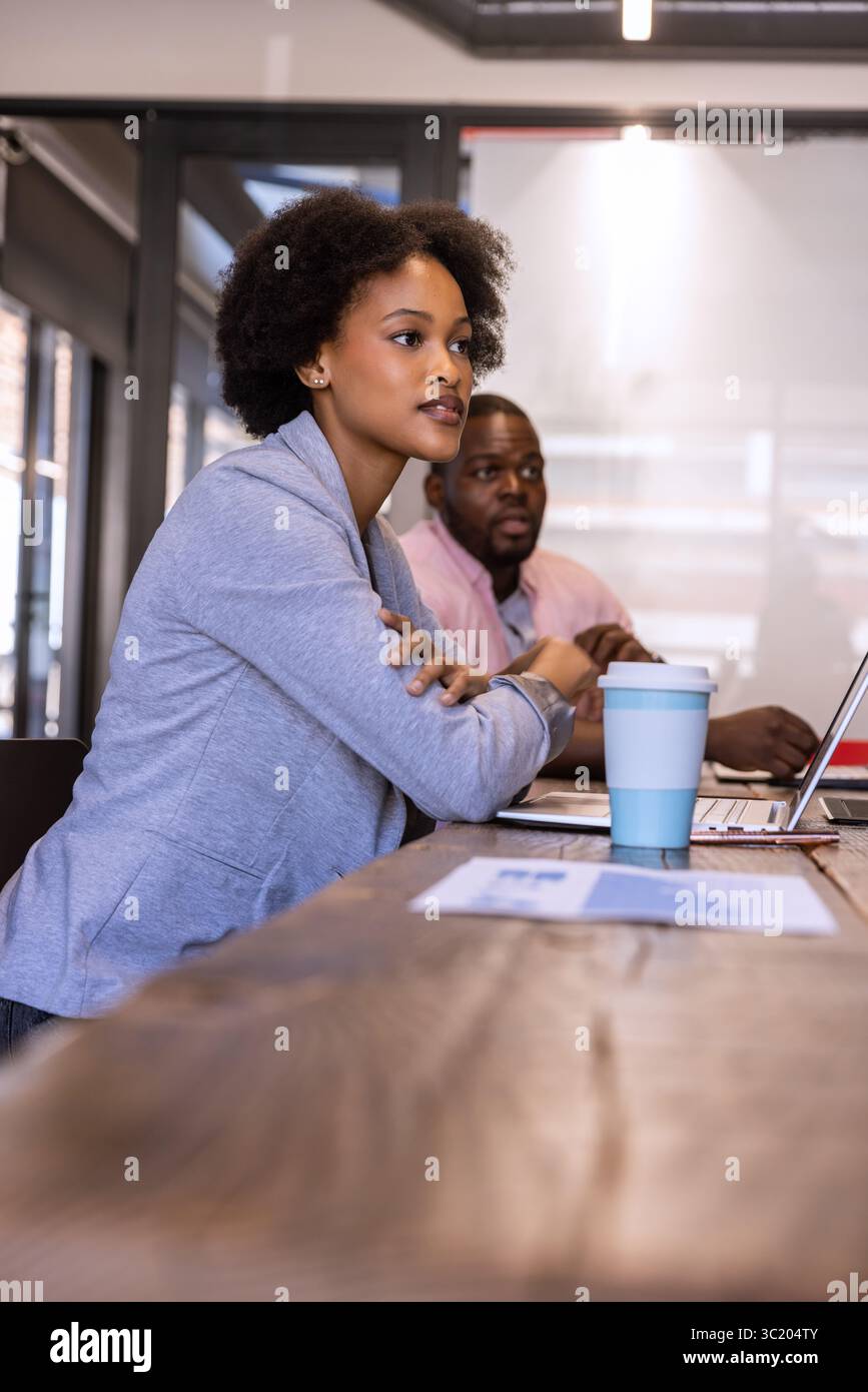 African American colleagues sitting in office reviewing document with laptop and cup, copy space Stock Photo