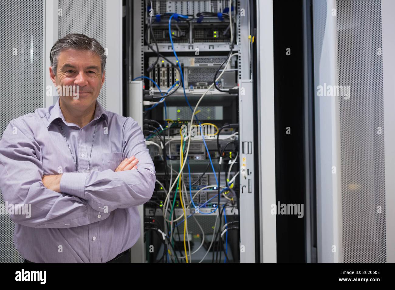 Male network technician monitoring server rack with colorful cables in ...