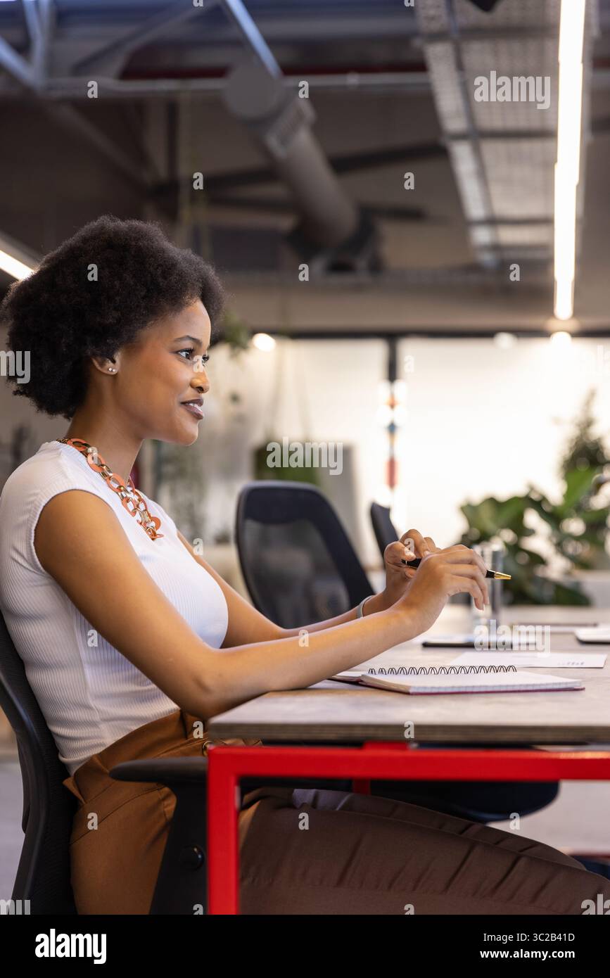 African American woman wearing business attire writing notes in notebook at office desk, copy space Stock Photo