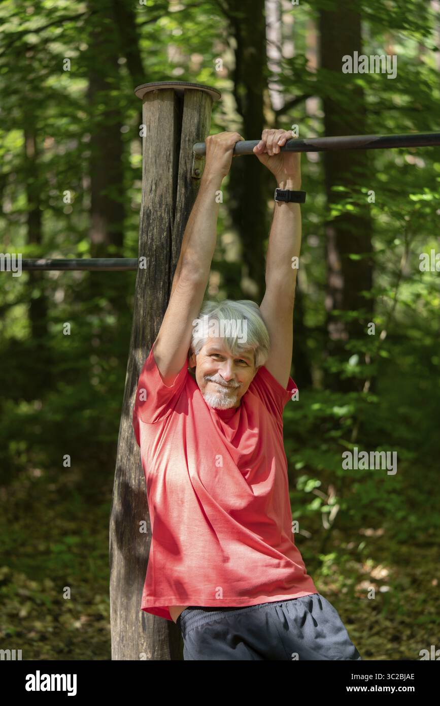 fit-older-man-exercises-on-the-trim-trail-in-the-forest-stock-photo