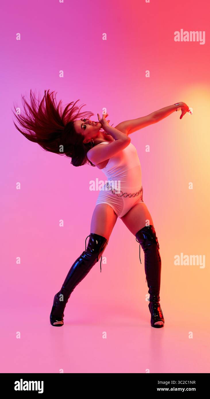 Energetic dancer in high heels striking pose on vibrant background Stock Photo