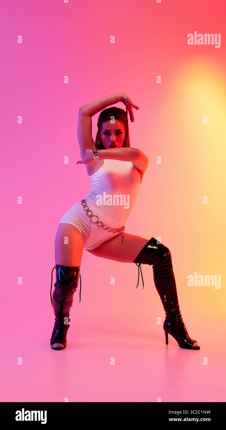 Dancer striking a pose in high heels against a colorful pink and orange backdrop Stock Photo