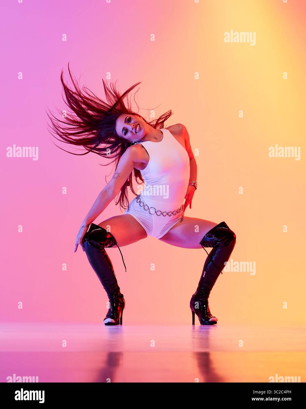Jazz funk performer dressed in white attire wearing high heels with vibrant backdrop Stock Photo