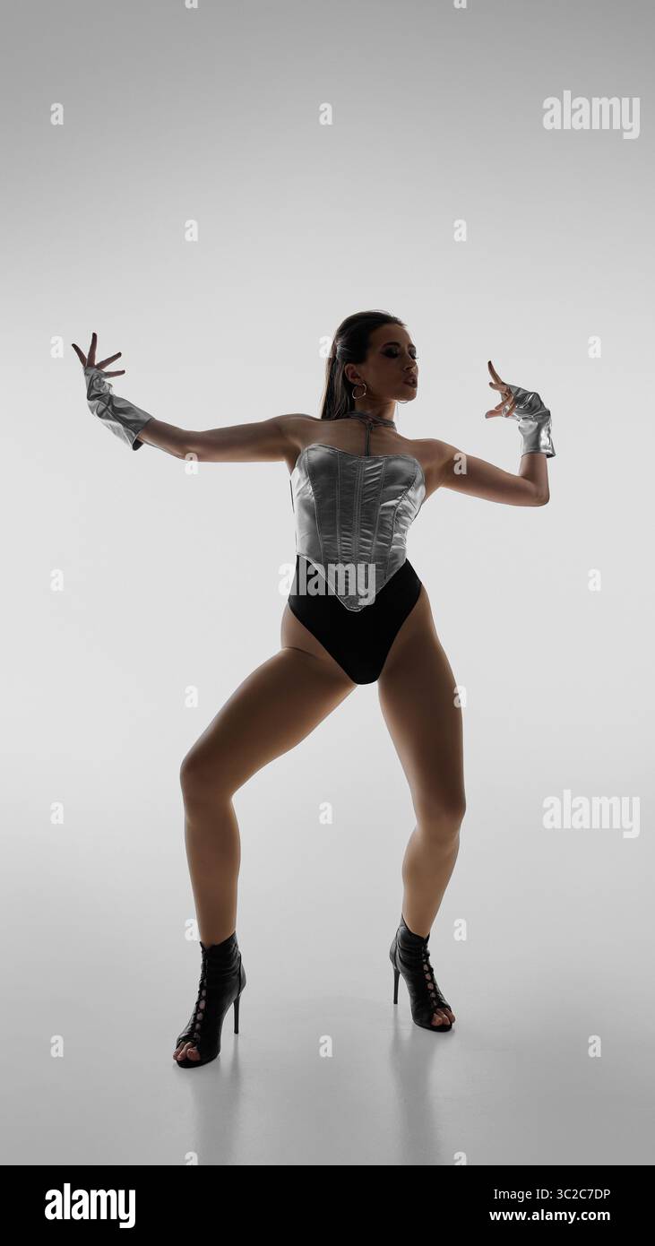 Elegant dancer striking dynamic pose in high heels against plain background Stock Photo