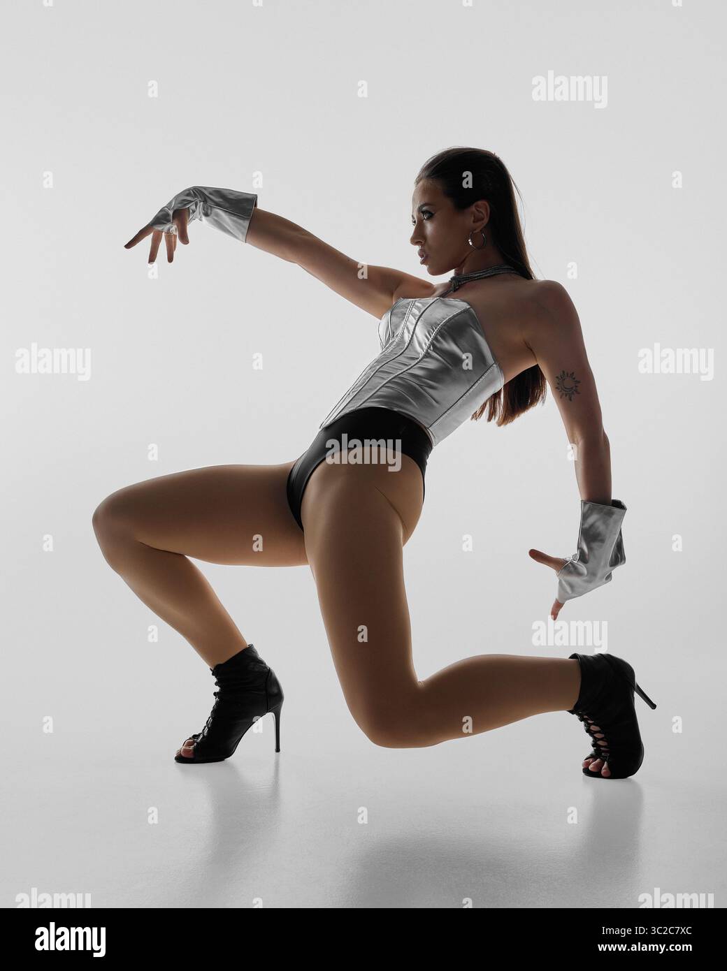 Dynamic jazz funk dancer striking a pose in high heels and metallic outfit Stock Photo