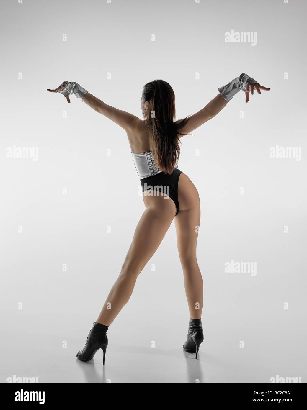 Dancer in high heels strikes dynamic pose against neutral background Stock Photo