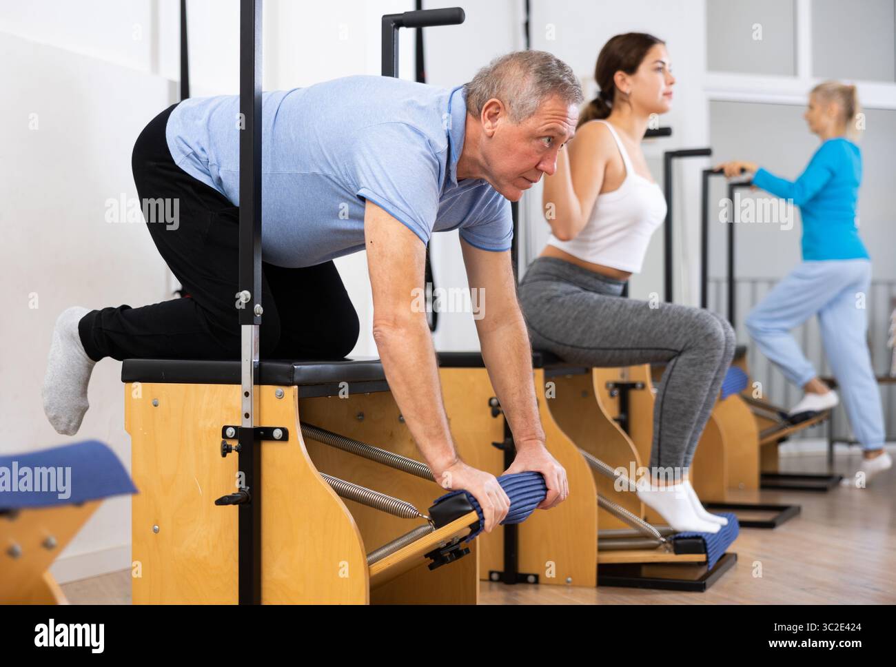 Focused man and women of different ages performing stretching exercises ...