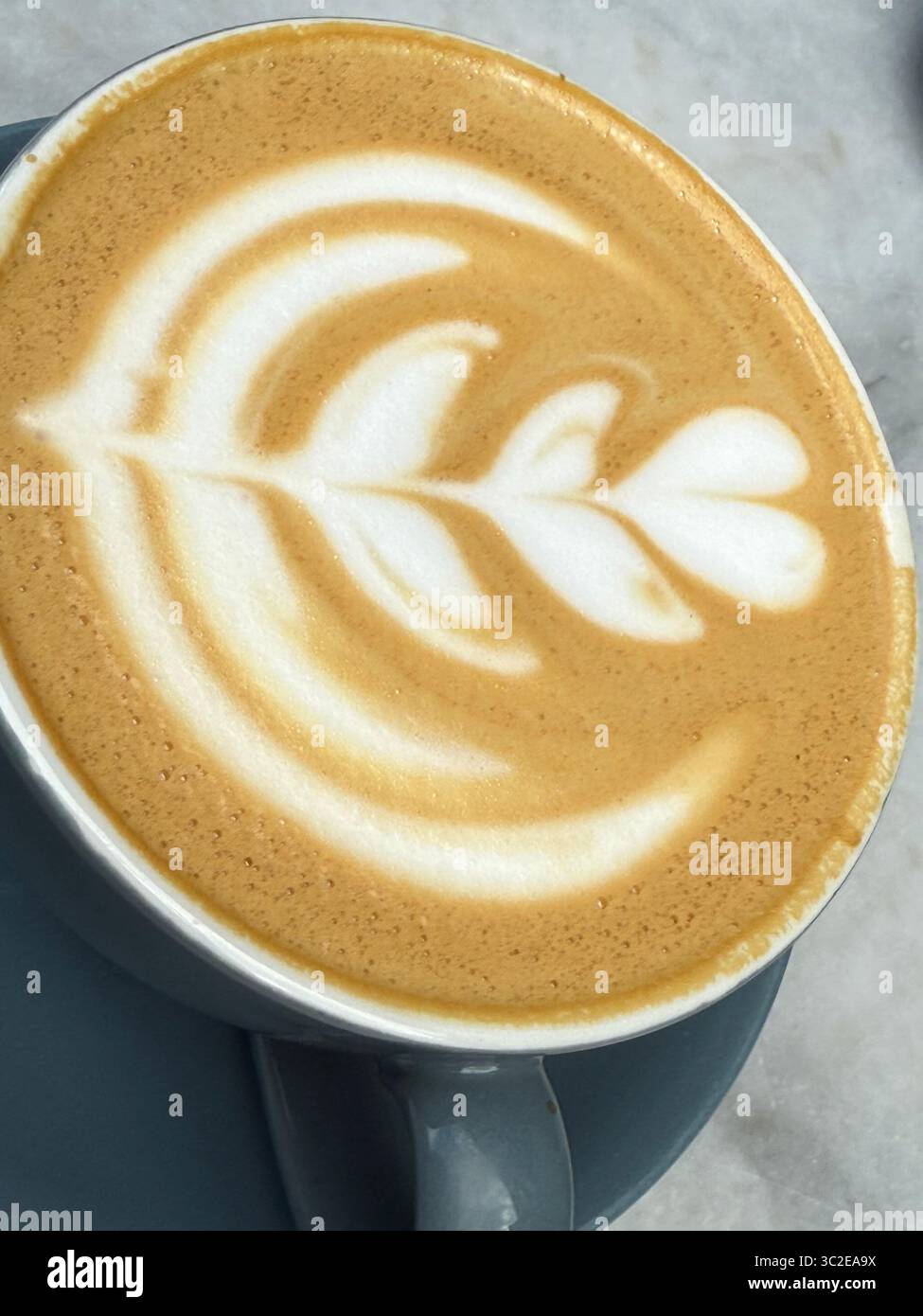 A latte art, barista’s creative design on top of a cup of coffee in a cafe - Smartphone Captured Stock Image