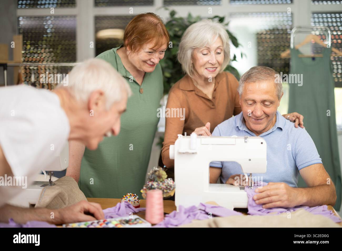 Retired students learning sewing from male instructor in tailoring workshop Stock Photo
