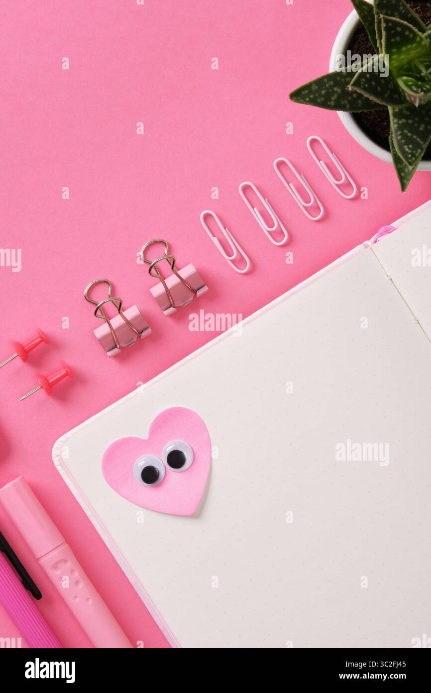 Heart-shaped sticker with eyes glued on the open page of a notepad ...