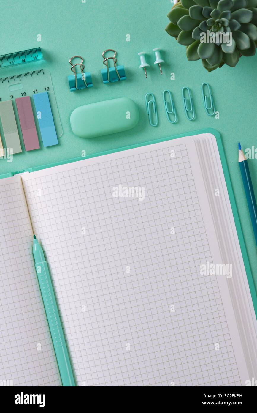 Top view of a desk with mint-colored stationery and an open notepad. A place for your text. Stock Photo