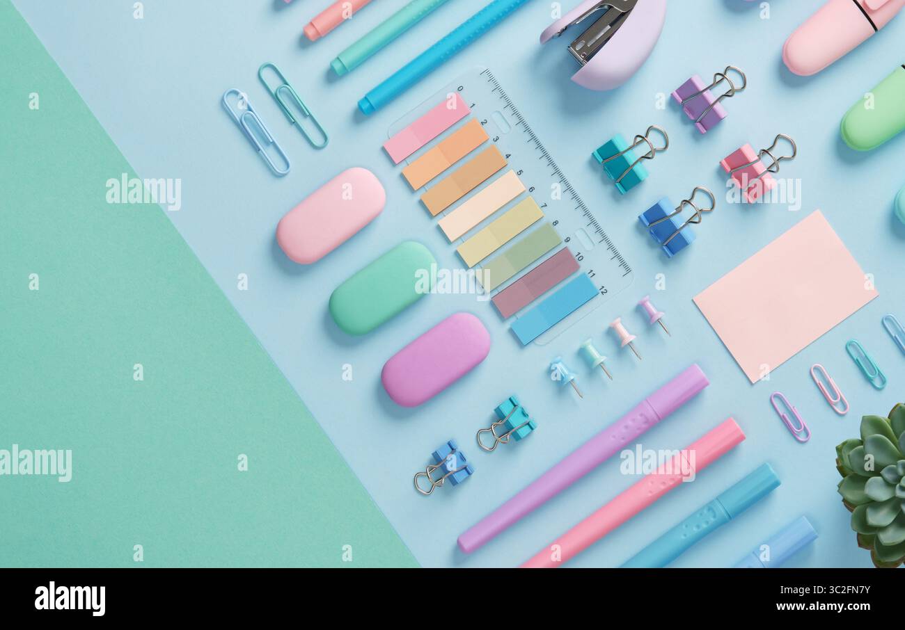 Stationery with markers, felt-tip pens, paper clips, erasers, stapler, pastel-colored stickers neatly arranged on a light blue and mint green backgrou Stock Photo
