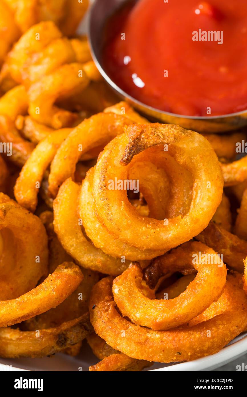 Unhealthy Seasoned Curly French Fries with Ketchup Stock Photo