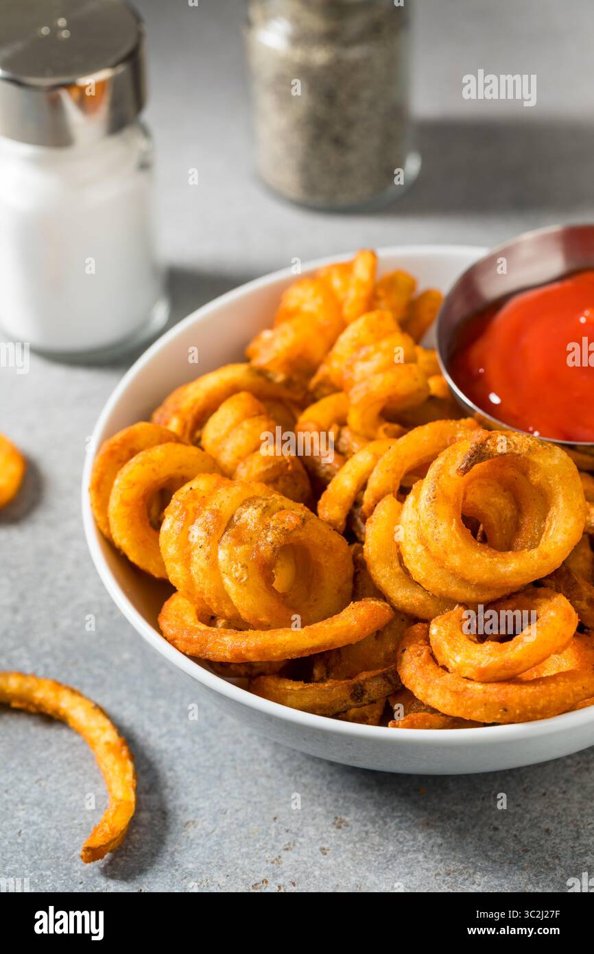Unhealthy Seasoned Curly French Fries with Ketchup Stock Photo