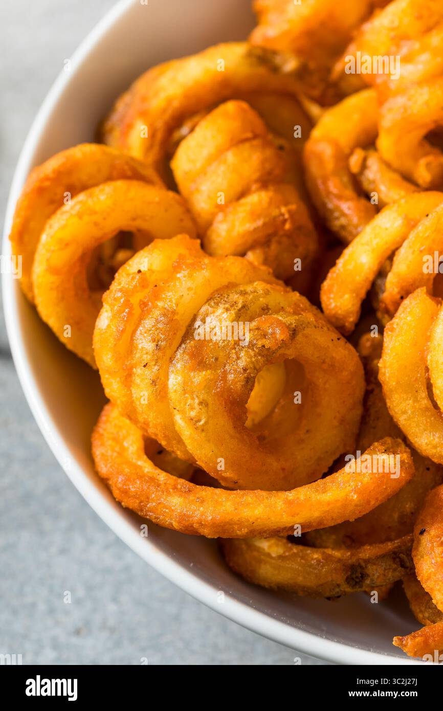 Unhealthy Seasoned Curly French Fries with Ketchup Stock Photo