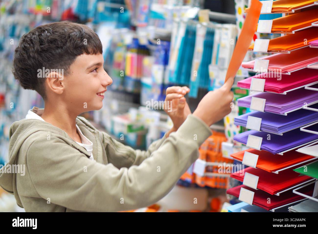 back to school. preteen boy shopping for colored cardboard, art