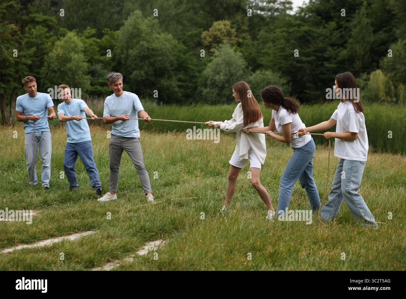 Team building. Group of happy people playing tug of war with rope ...