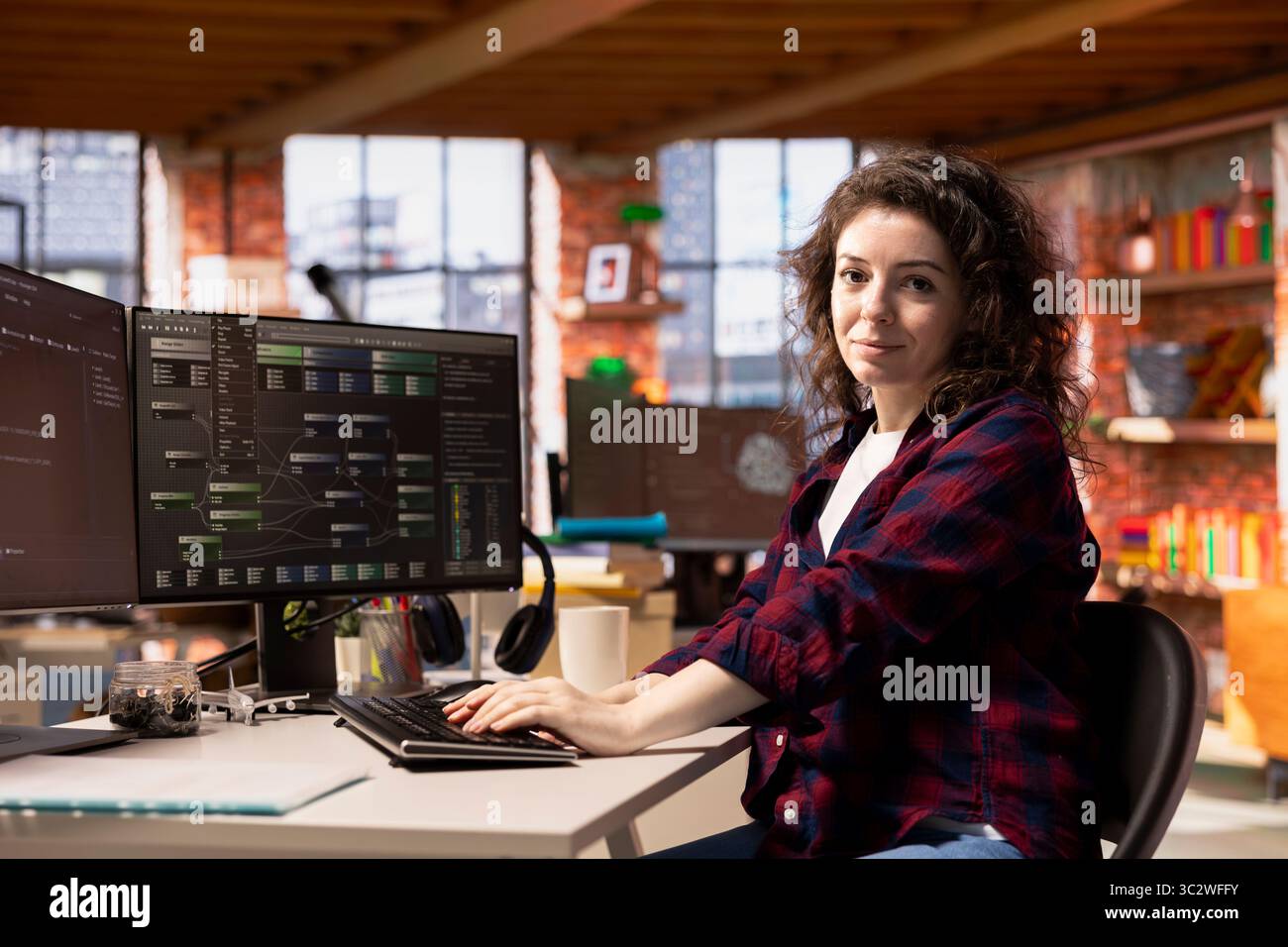 Portrait of smiling programmer coding advanced AI algorithm in startup workspace, refining machine learning models to enhance automation. Happy woman using coding platform in Silicon Valley office Stock Photo
