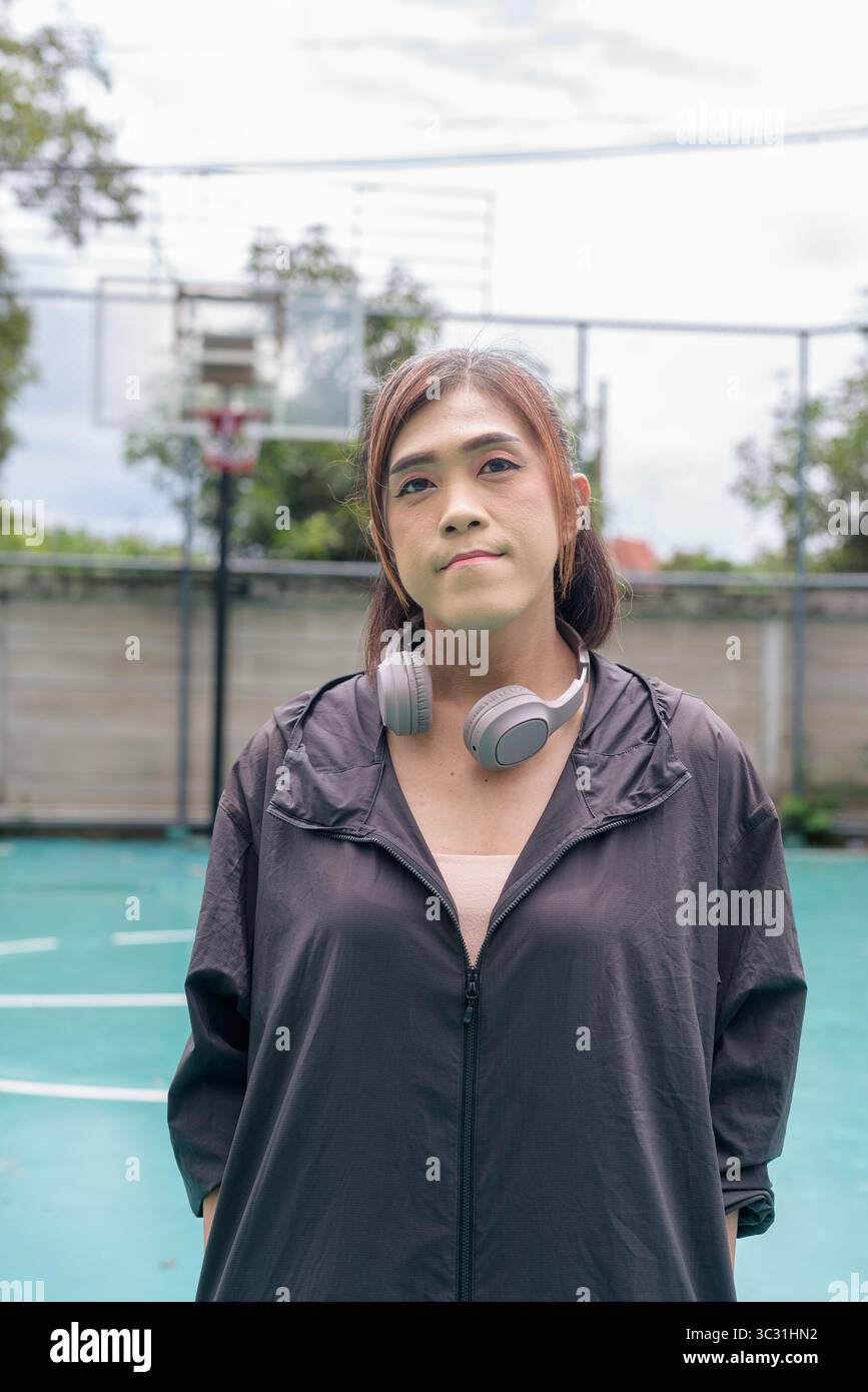 Portrait of a fit transgender woman standing on outdoor basketball court, promoting strength and urban fitness lifestyle Stock Photo