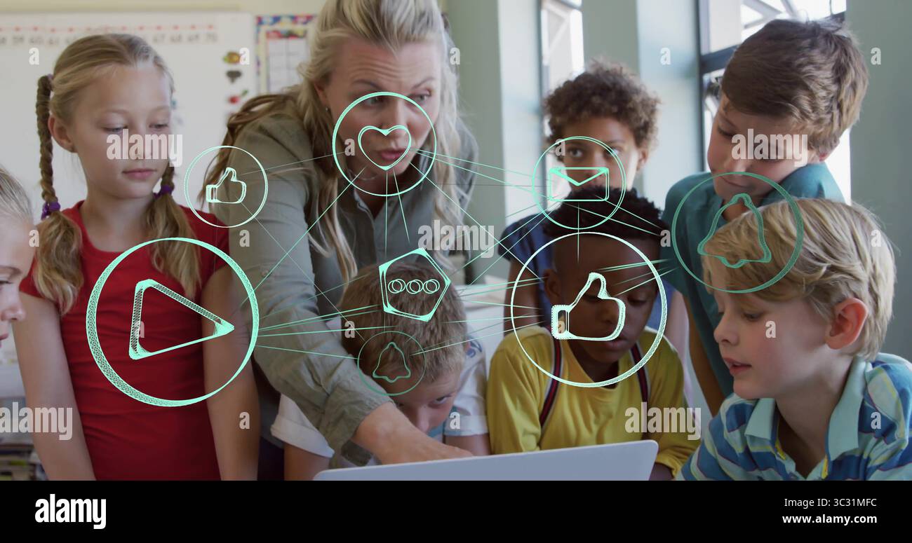 Pointing teacher guiding students around laptop in classroom, with social media icons Stock Photo
