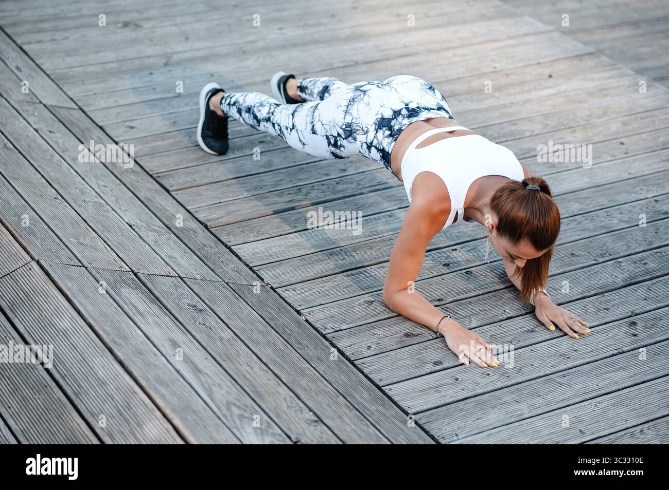 Woman Doing Push-Ups on Wooden Deck Stock Photo