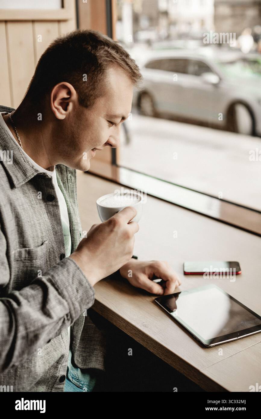 Man drinking coffee and using tablet in cafe Stock Photo