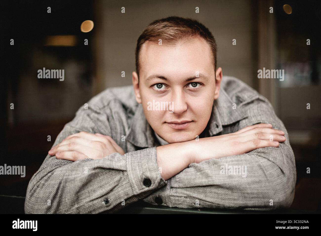 Man resting head on arms with calm expression Stock Photo