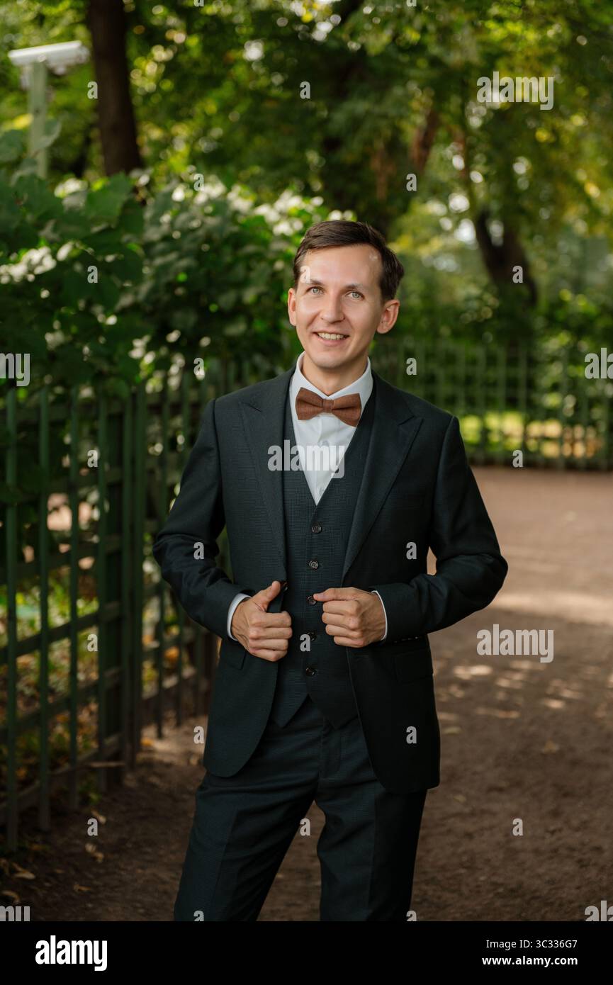 Man in formal attire smiling in a park setting Stock Photo