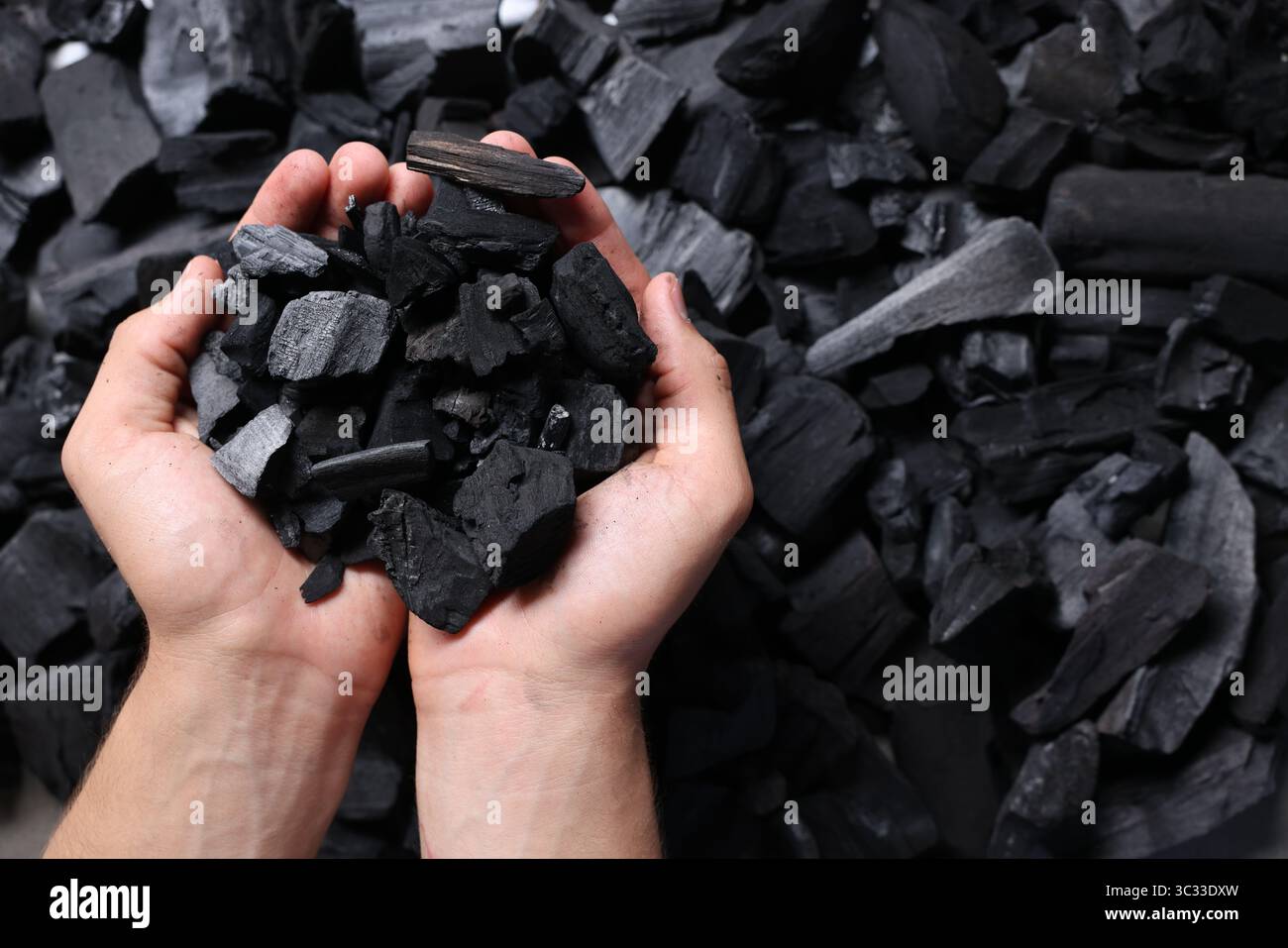 Man with black coals over pile, top view Stock Photo