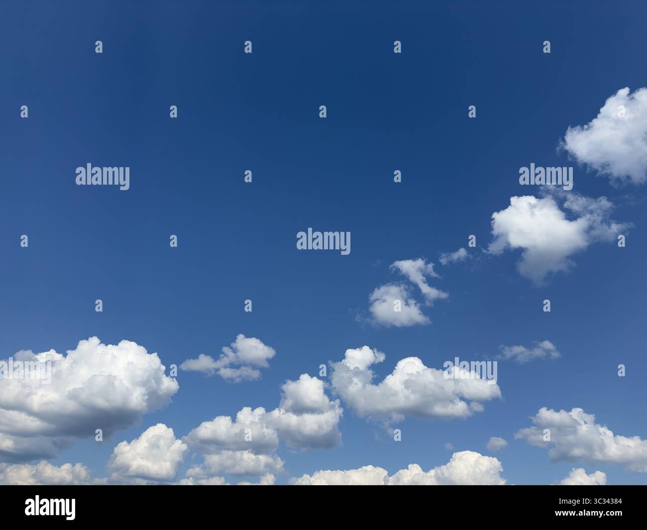 Beautiful display of white puffy clouds against a clear blue sky on a sunny day. Stock Photo