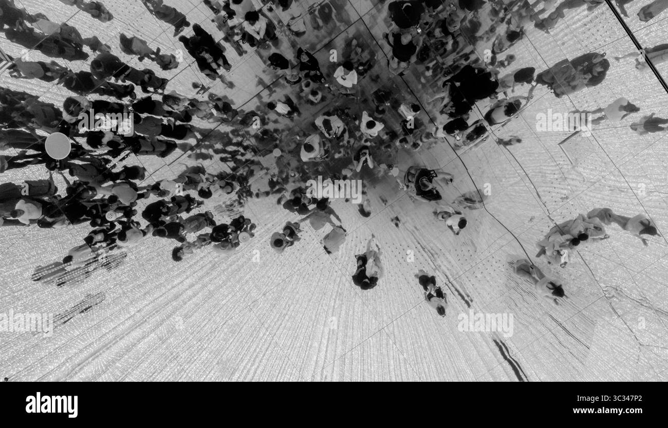 Tourists walking on a mirrored ceiling creating a mesmerizing and futuristic atmosphere, Crowd of people from above Stock Photo