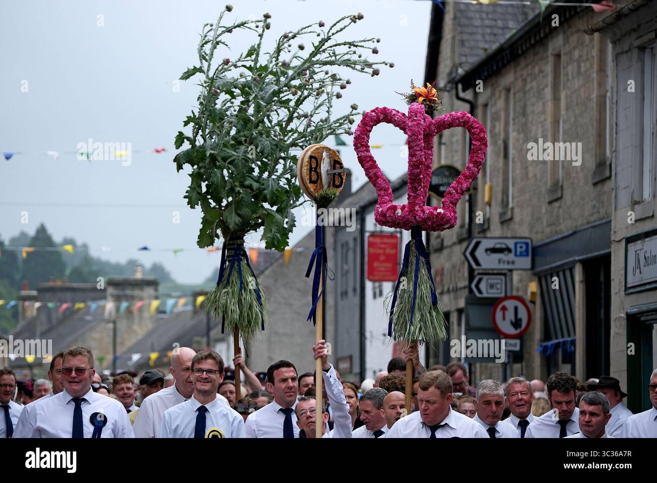 Langholm, UK. 25th July, 2025. Carrying the emblems of the Common Riding, a parade makes their way through the streets during the towns common riding on July 25, 2025 in Langholm, Scotland. A common riding is an equestrian tradition that mainly takes place in the Scottish Borders in Scotland where men and women ride out of the town and along its borders to commemorate the practices from the 13th and 15th centuries when there were frequent raids on the Anglo-Scottish border known as the Border Reivers. In Langholm this event dates back to 1759. ( Credit: Rob Gray/Alamy Live News Stock Photo