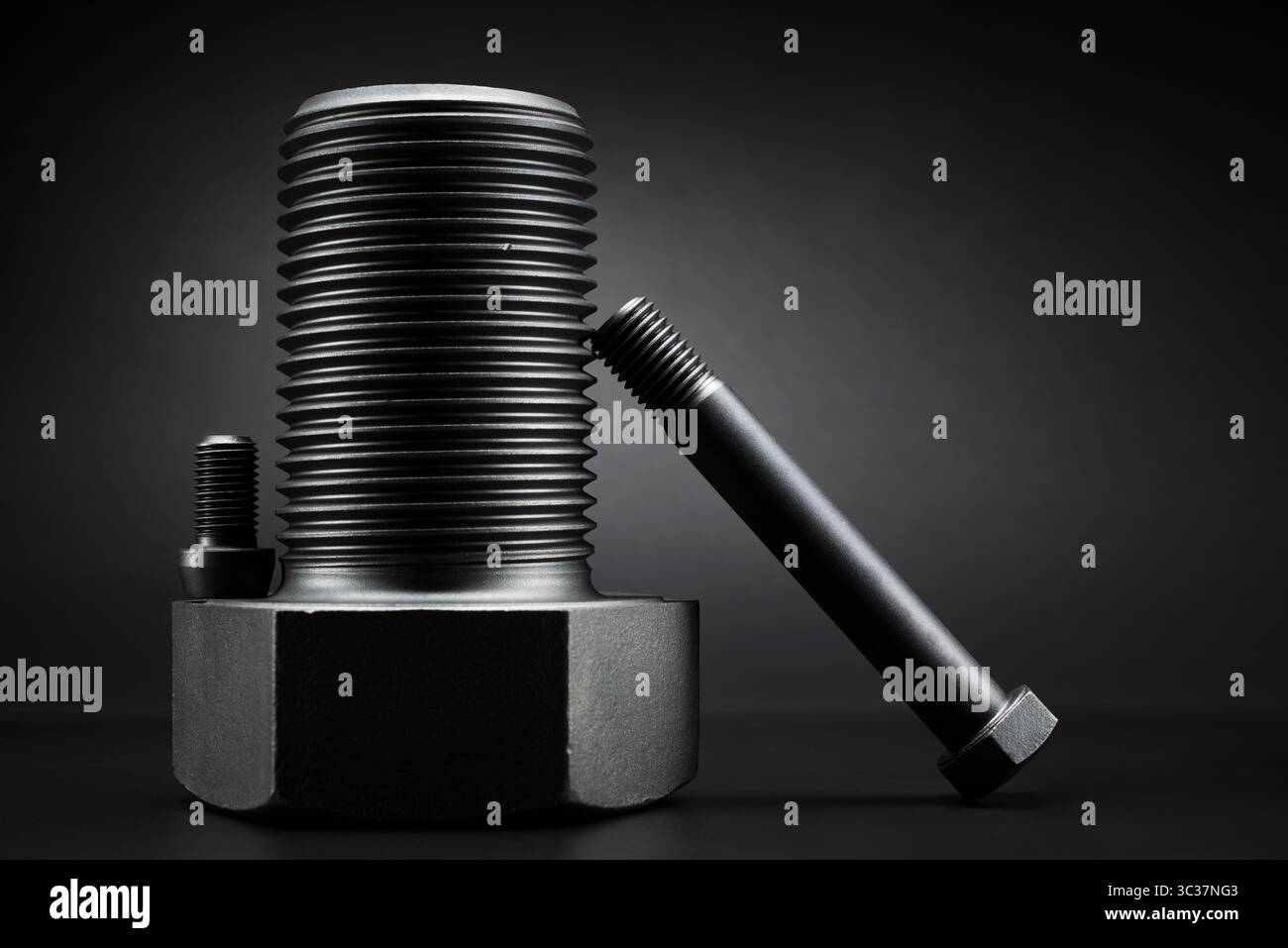 Variety of large black steel screws on black background. Stock Photo