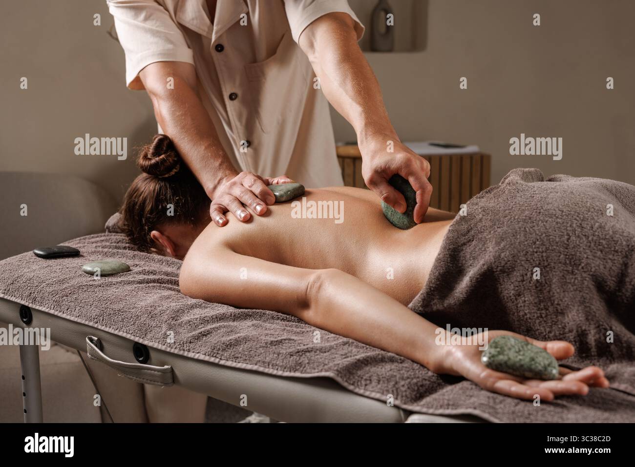 Hot stone massage promotes muscle relaxation, wellness, and peace in a calming spa environment Stock Photo