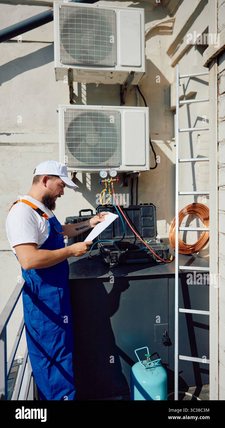 Technician inspecting rooftop air conditioning system with tools and equipment Stock Photo