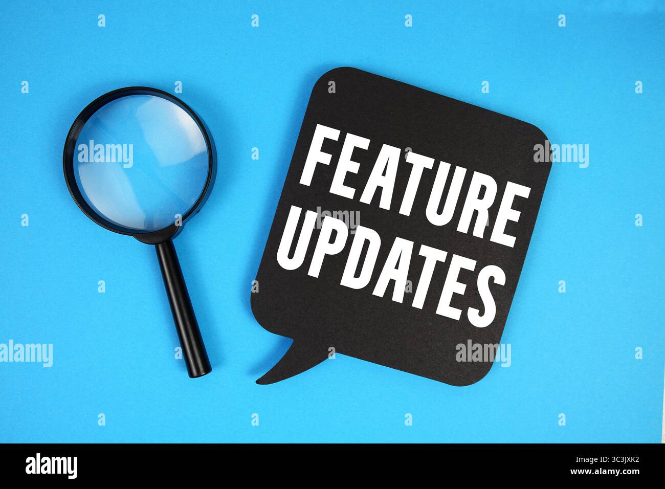 Feature Updates text with magnifying glass on blue background Stock Photo