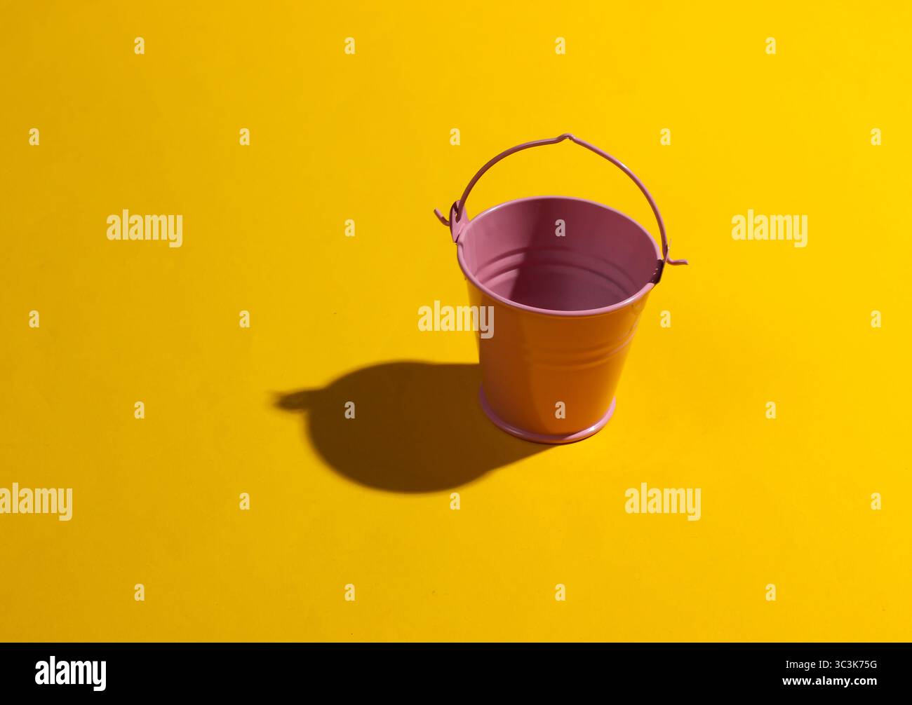 Empty mini pink bucket on a yellow background. Studio shot with shadow Stock Photo