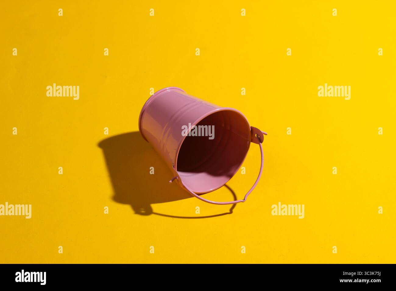 Empty mini pink bucket on a yellow background. Studio shot with shadow Stock Photo