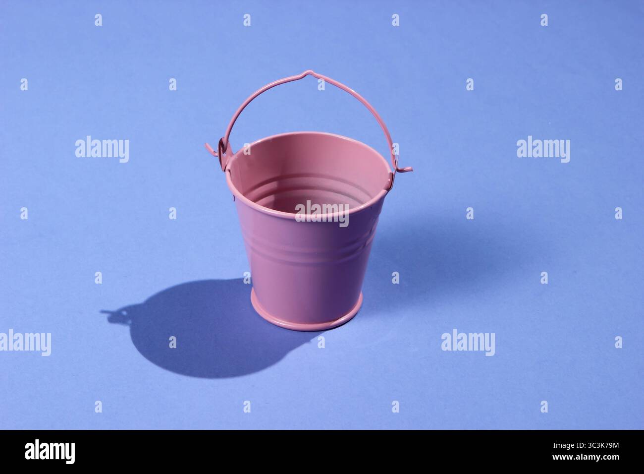 Empty mini pink bucket on purple background. Studio shot with shadow Stock Photo
