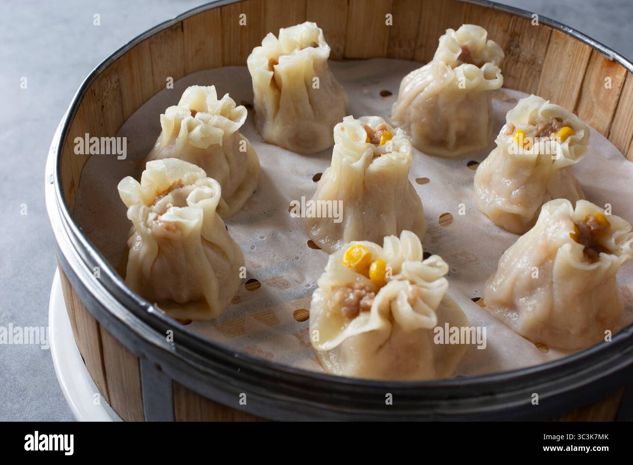 A closeup view of several shu mai dumplings inside a bamboo steamer basket. Stock Photo