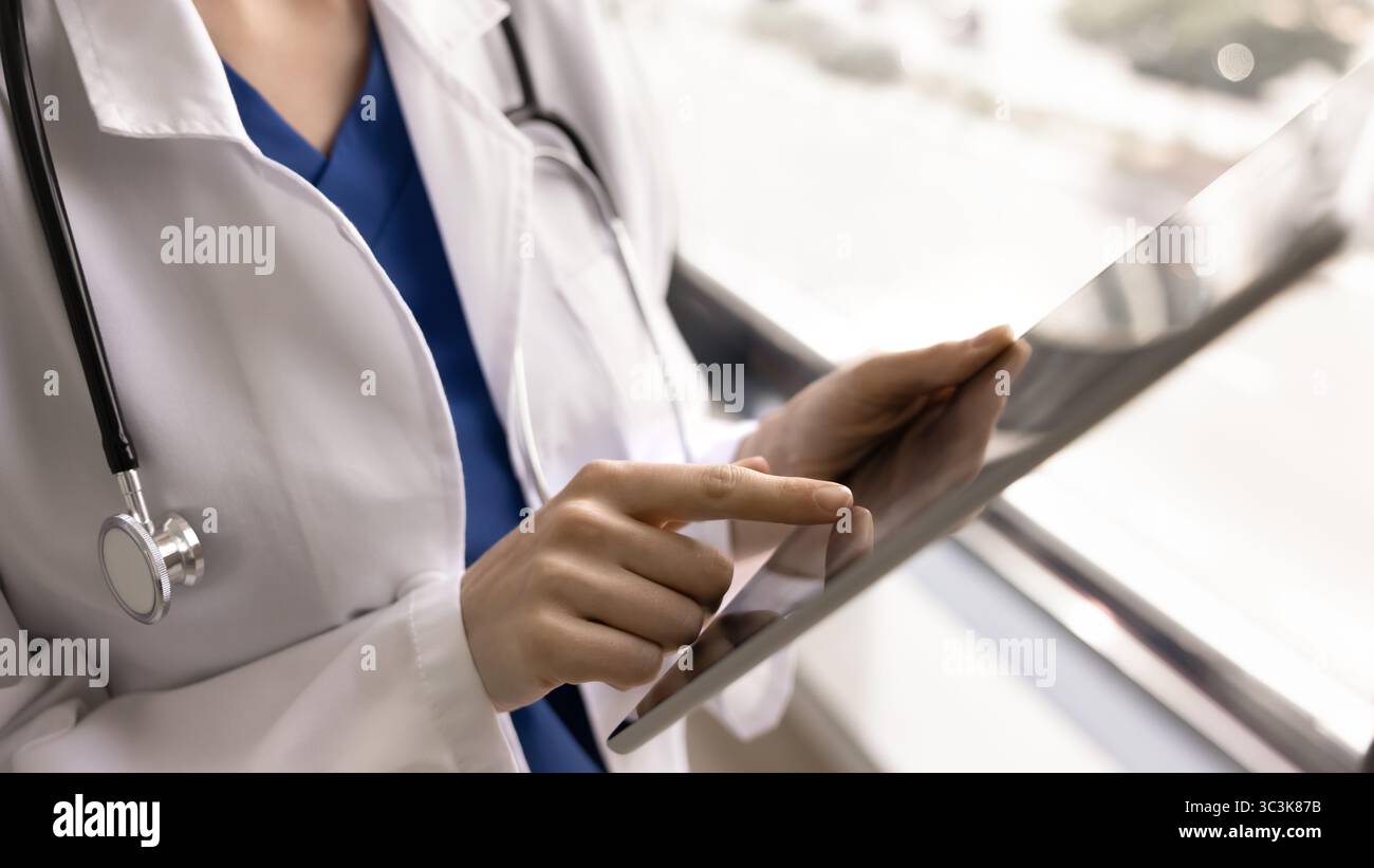 Young female doctor using tablet pc, touching screen with finger Stock Photo