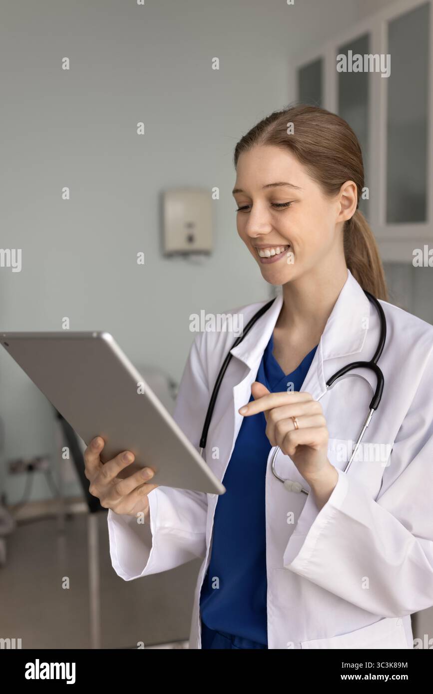 Positive young 20s general practitioner woman using tablet Stock Photo